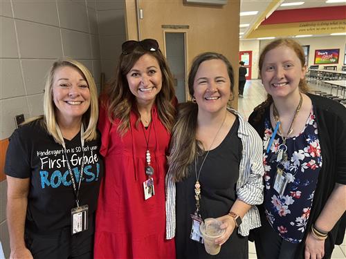 Rainbow faculty members (four ladies) smiling in hallway